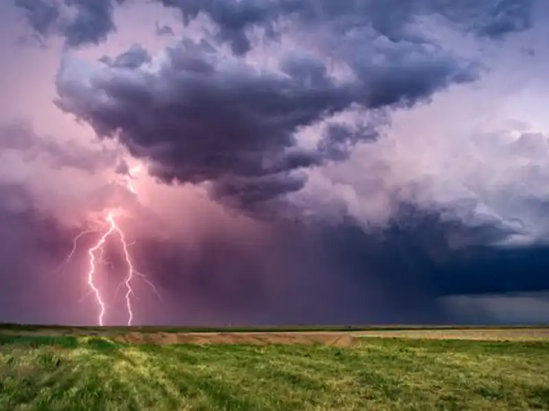 thunderstorm with a bolt of lightening striking an open field