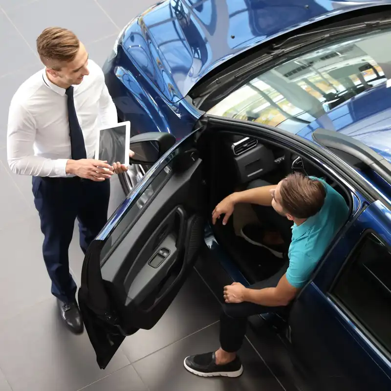 Young car salesman working with client in dealership.