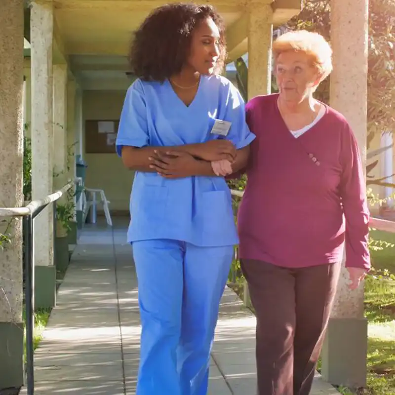 African female doctor talking to elderly retired woman in the hospital yard.