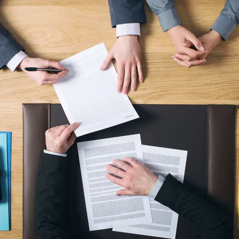 Business man and woman sitting at the lawyer's desk and signing important documents, hands top view.
