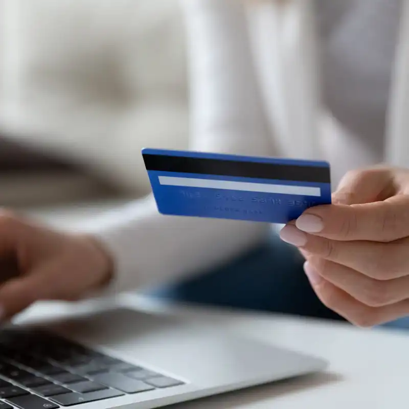 Close up image female sit at table using laptop hold credit card makes payment.