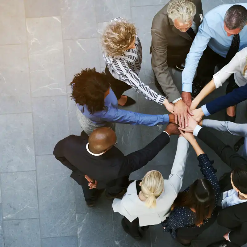 aerial view of diverse coworkers with hands on hands.