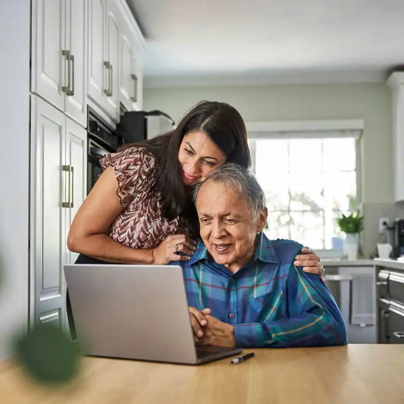 Daughter assisting father on how to use the computer.