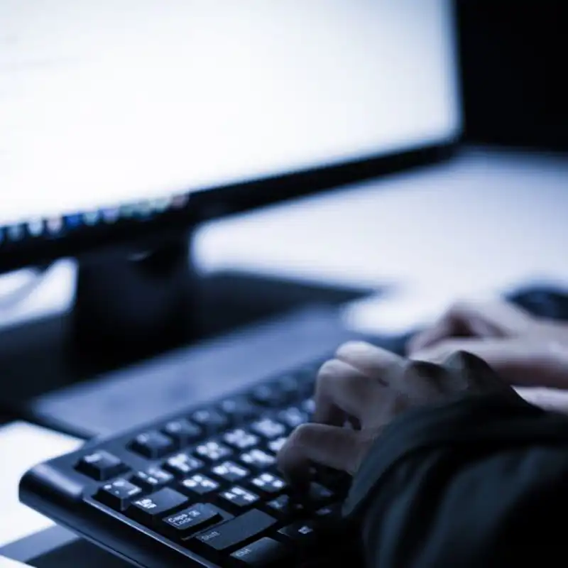 Hooded computer hacker stealing information with laptop.