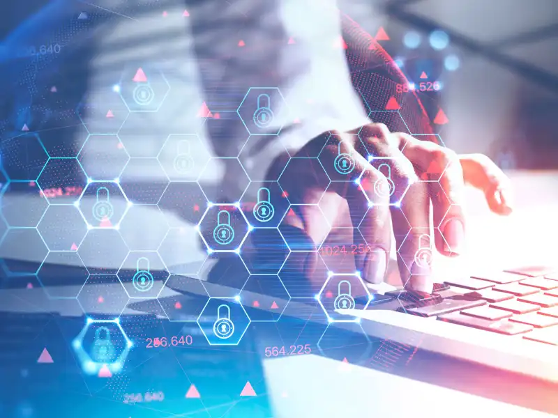 Cyber security symbols next to a man typing on a laptop