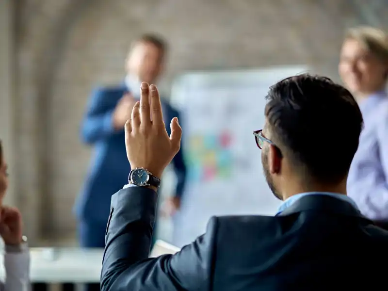 Business man raising his hand during a presentation.