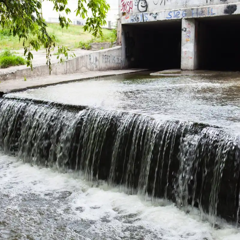 Water stream flowing out the underground tunnel into a river.
