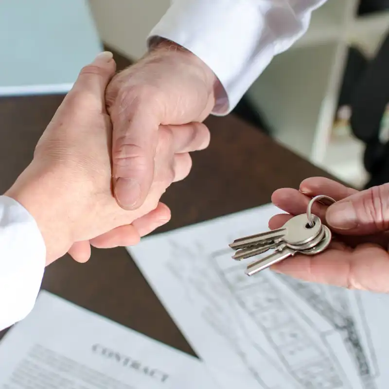 Estate agent giving house keys to customer after contract signature.