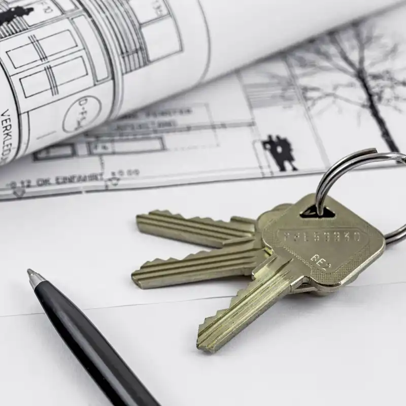 Close up of house keys with a rental agreement contract in the background.