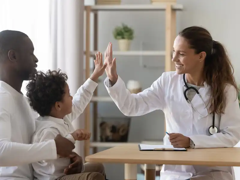 Pediatrician welcomes small kid patient and his dad at medical check up appointment