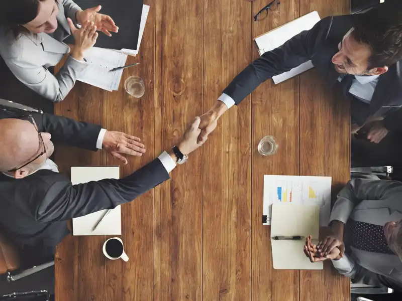 Overhead view of two businessmen shaking hands at a table.
