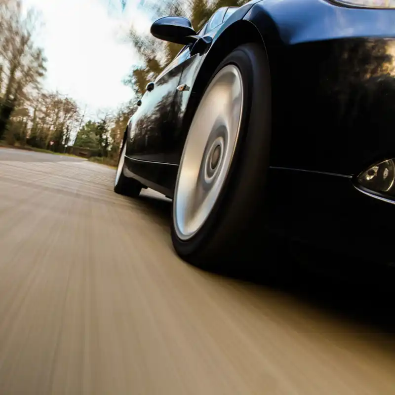 Close up of a tire of a speeding car driving down the road.
