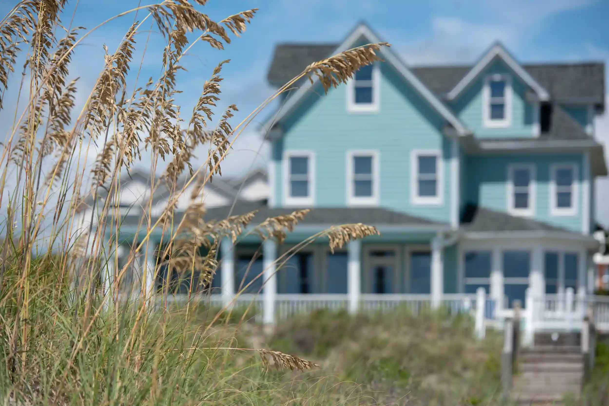 Blue beach house with grass in the foreground