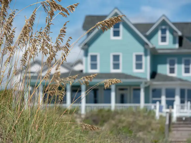 Blue beach house with grass in the foreground