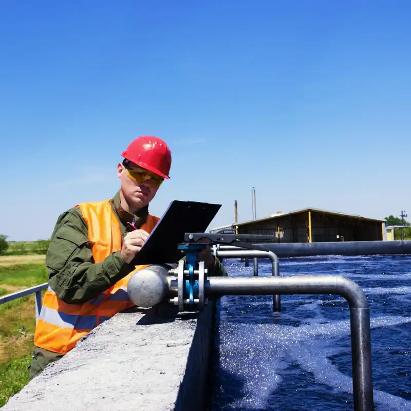 Worker inspecting a valve at a sewage pond.