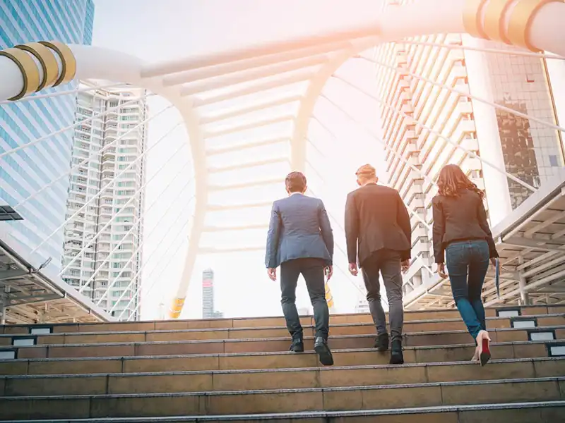 Three people walking up staris.