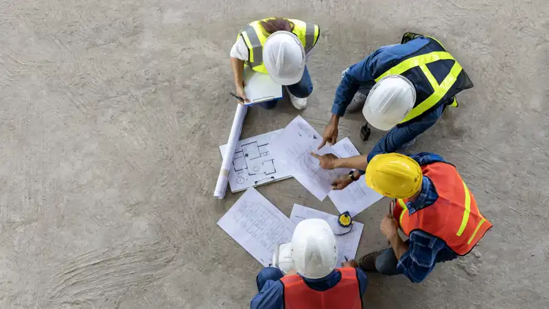 aerial view of construction workers looking at blueprints