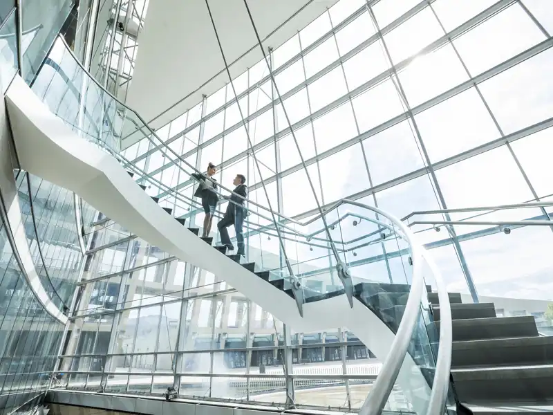 Two co-workers having a conversation on a spiral staircase.