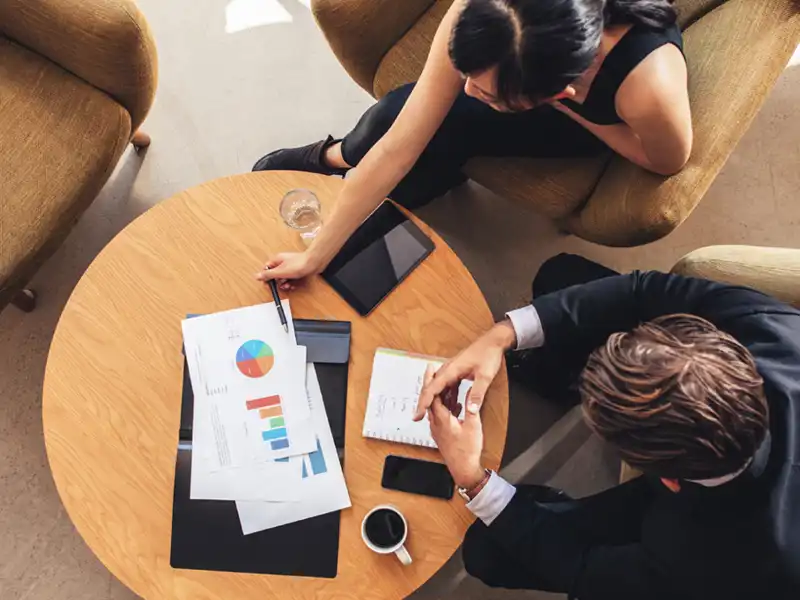 business people seated at desk with graphs and notebooks.