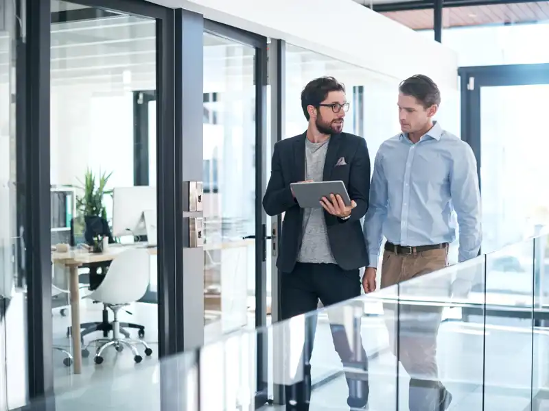 Two people looking at a laptop while walking.