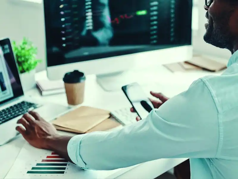 man sitting at desk with bar graphs on a laptop