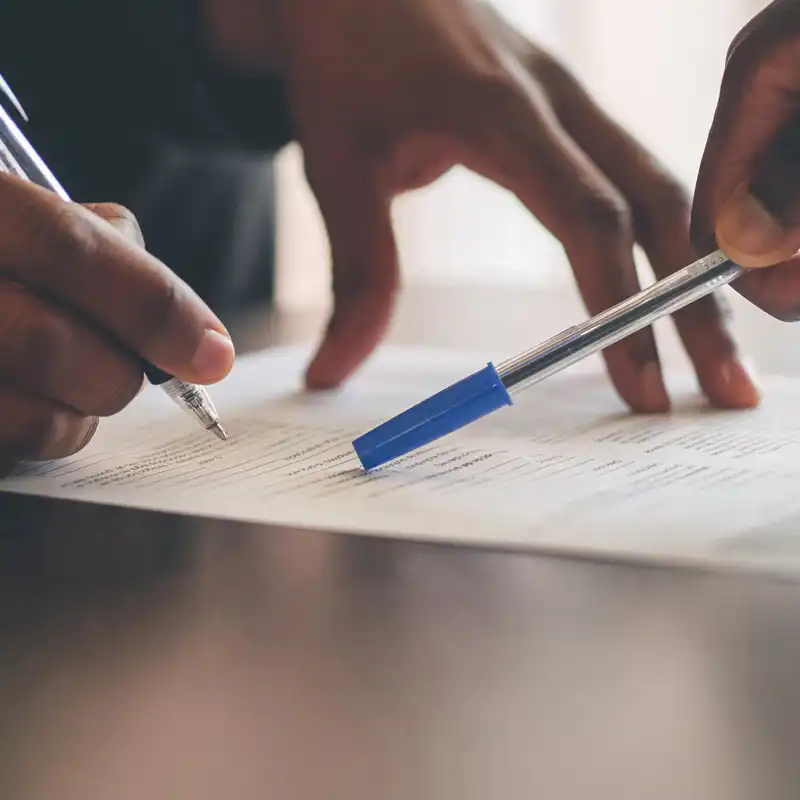 people looking over paperwork with pens