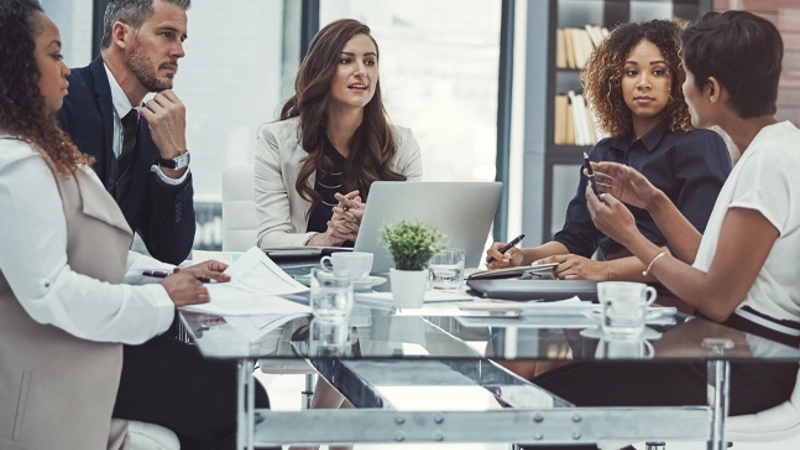 Five people sitting around a conference table having a discussion.