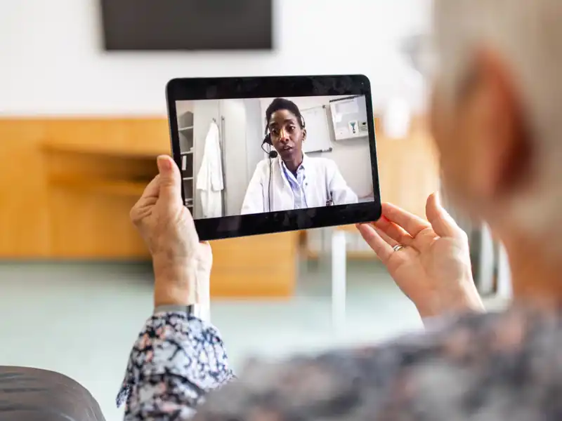 A woman uses a tablet for a telemedicine call