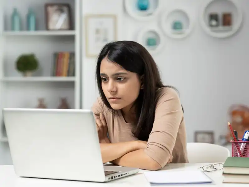 A woman studies a laptop screen
