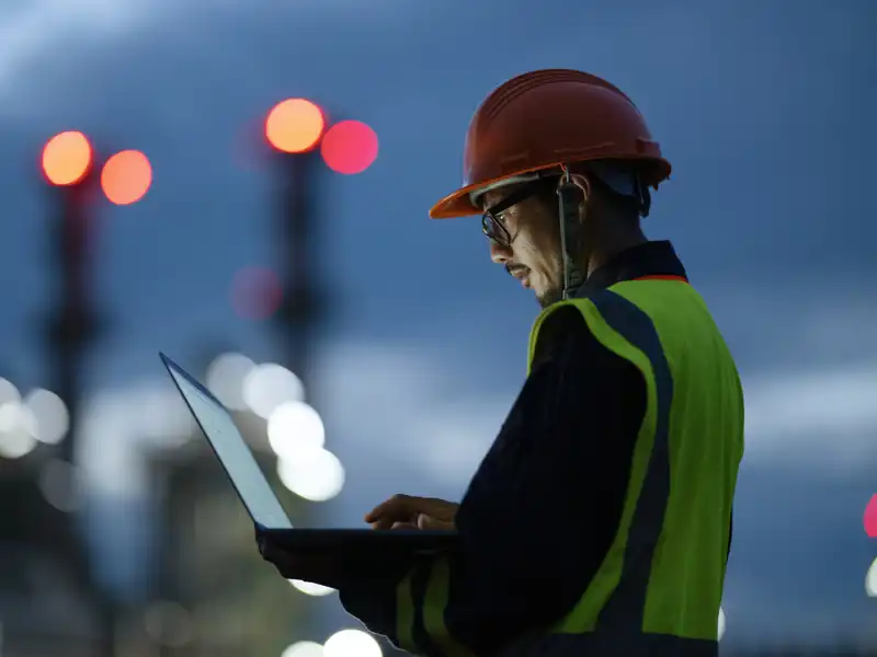 Construction worker looking at a laptop in the early morning.