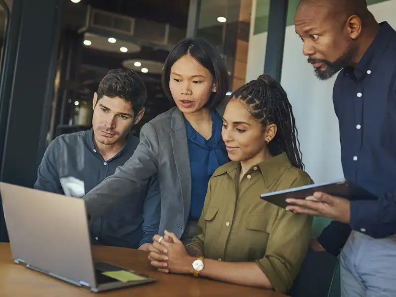 Coworkers around a laptop.