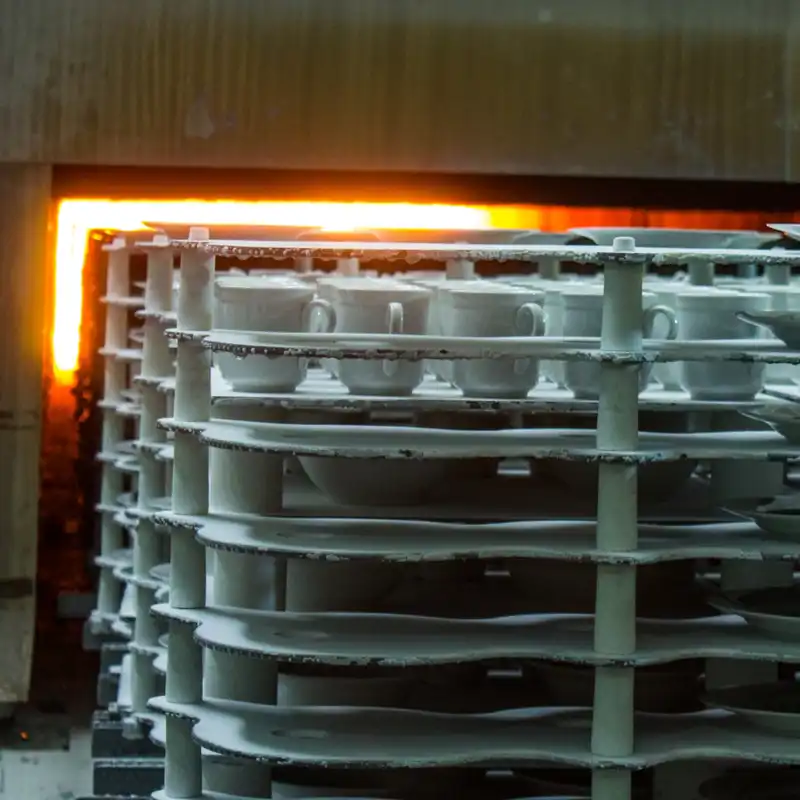 Ceramic coffee mugs being placed into an oven.