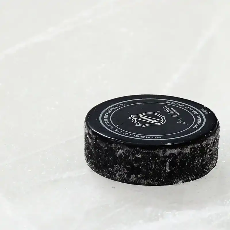 Close up of a hockey puck on the ice featuring the NHL logo