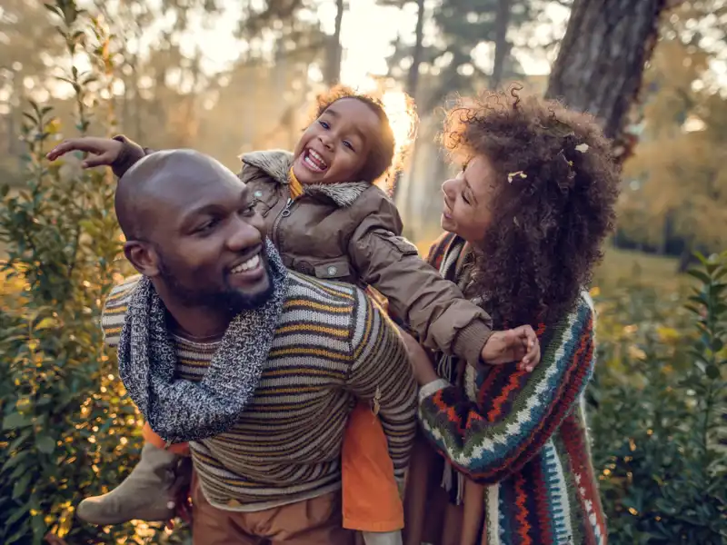 Black family walking outside with child on father's shoulders