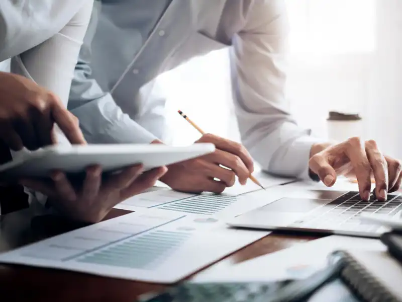 Close up of people working on a tablet and laptop