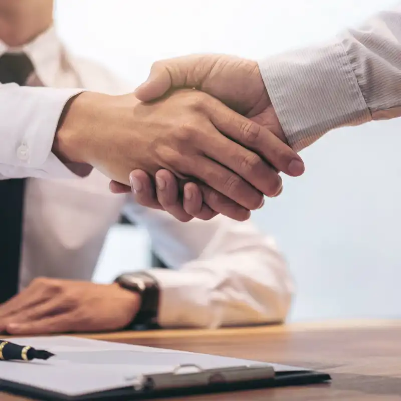 Agent and customer shaking hands after signing contract documents for realty purchase.
