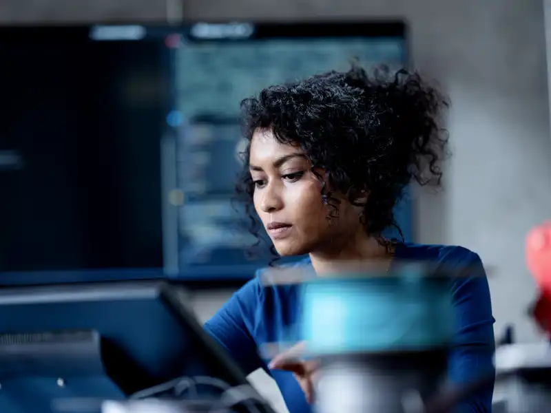 Business woman typing on a computer sitting at her desk in a modern office.