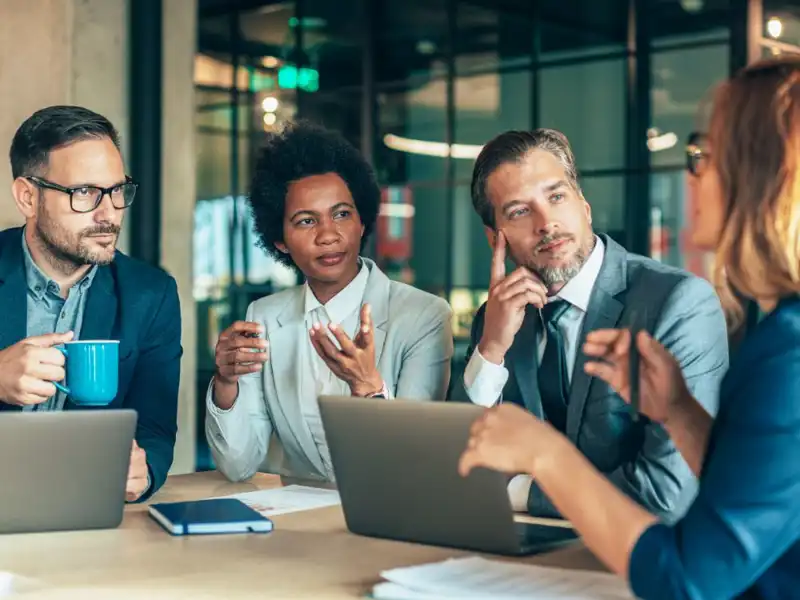 Four people with computers and documents having a discussion