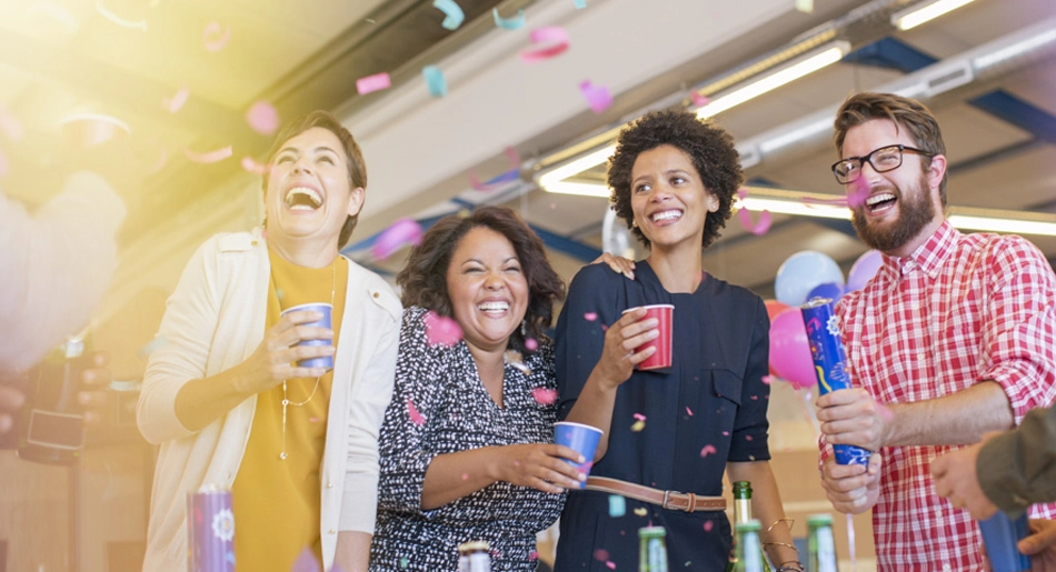 Four people laughing and smiling during a celebration