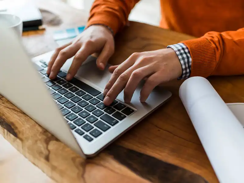 Hands tap on a laptop computer