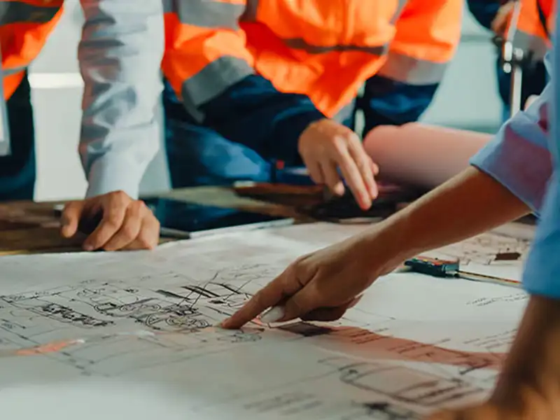 Construction professionals study blueprints on a table.