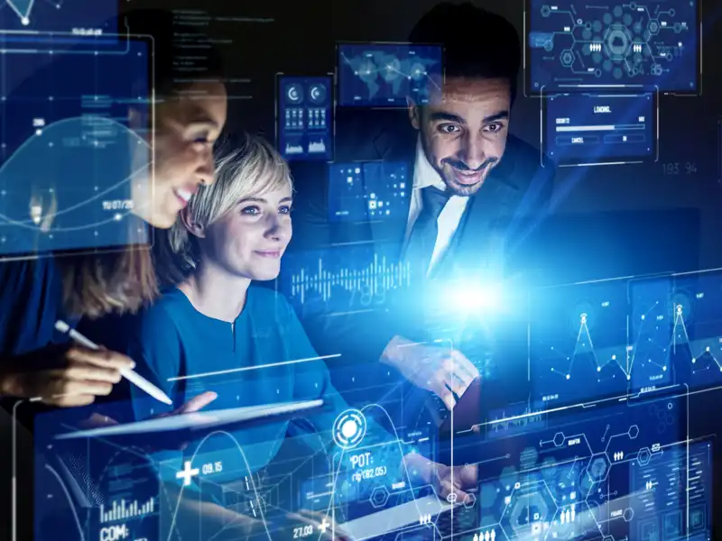 Three coworkers looking at a screen with data and graphs.