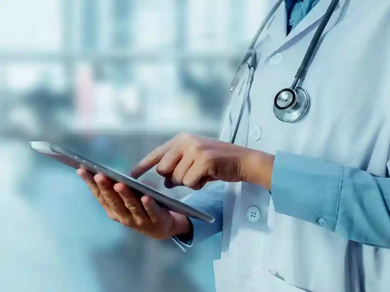 Medical professional wearing a stethascope and using a tablet.