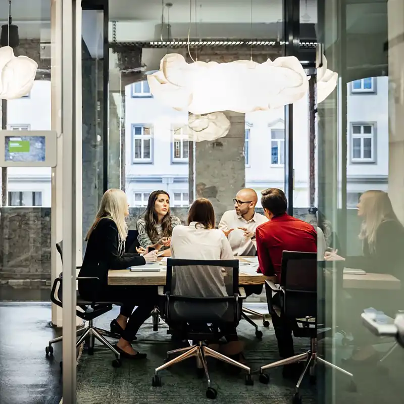 An office team meets in a modern minimalist conference space.