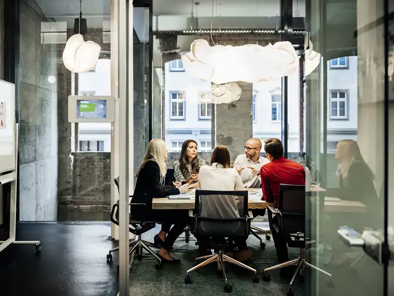An office team meets in a modern minimalist conference space.