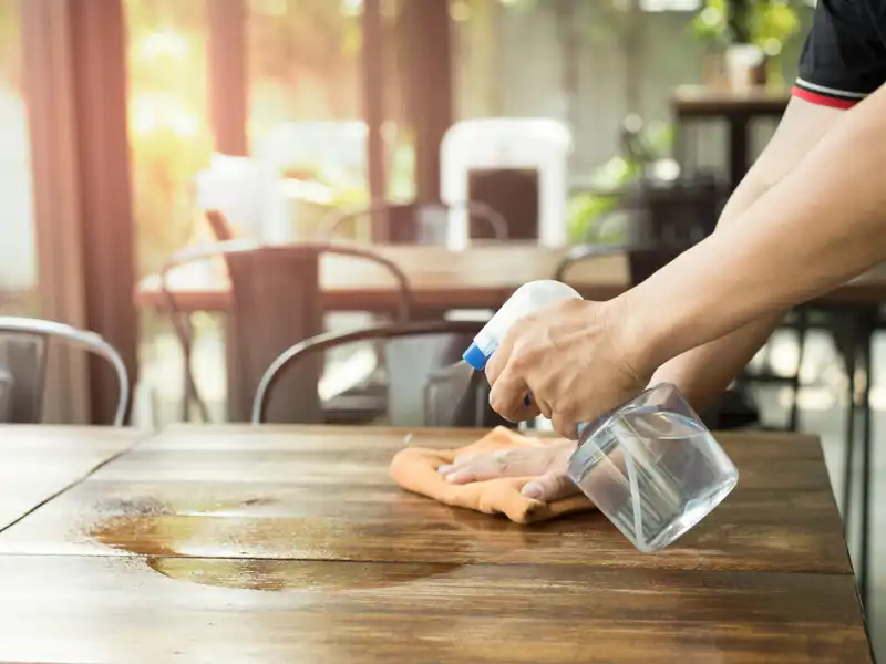 Cleaning a table with a solution.
