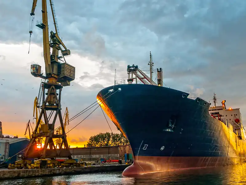 A cargo ship is moored at a loading dock