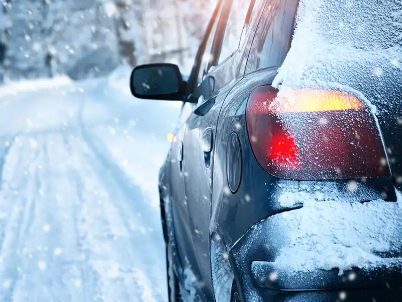 A car ventures down a dangerous snowy road