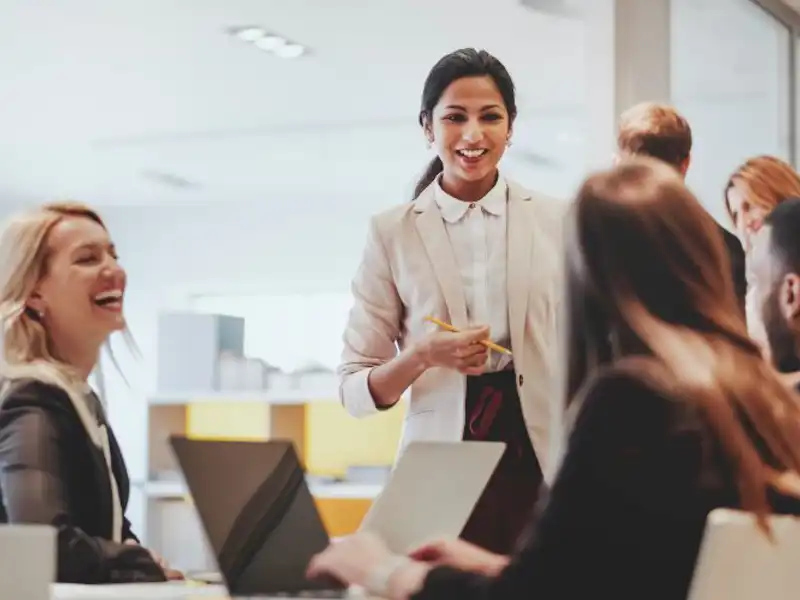 Three women and a man at a conference table smiling and talking
