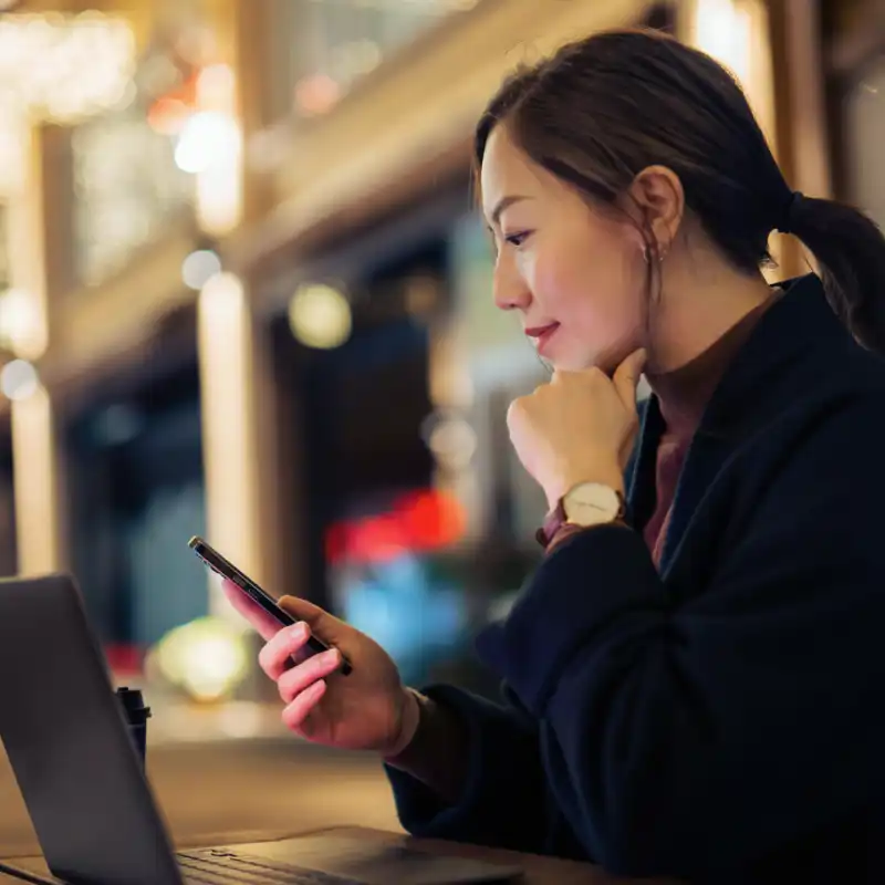 Young woman on cell phone in front of a computer.